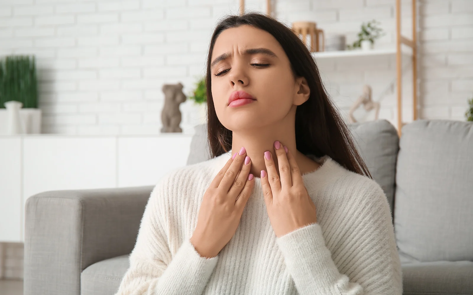 Woman touching the front of her neck near her thyroid gland
